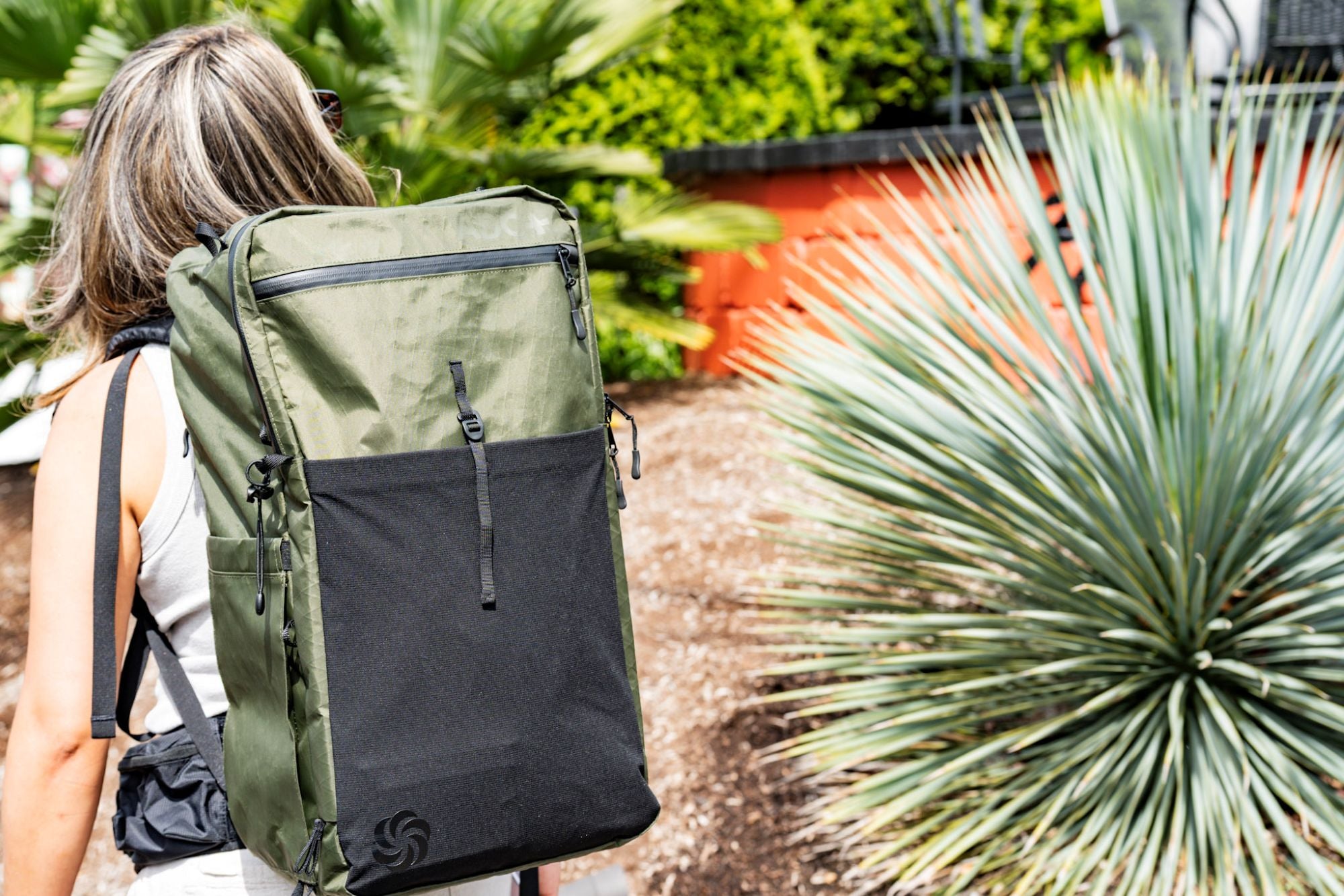 ADC travel backpack in moss color walking down the street