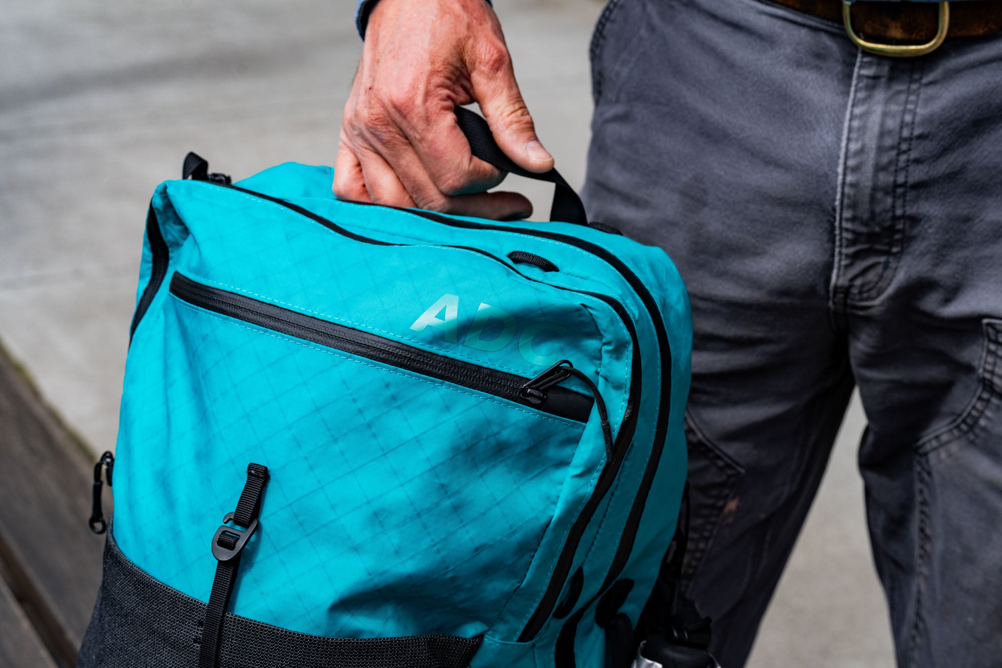 Teal ADC being held by its top haul loop while walking around the city. 
