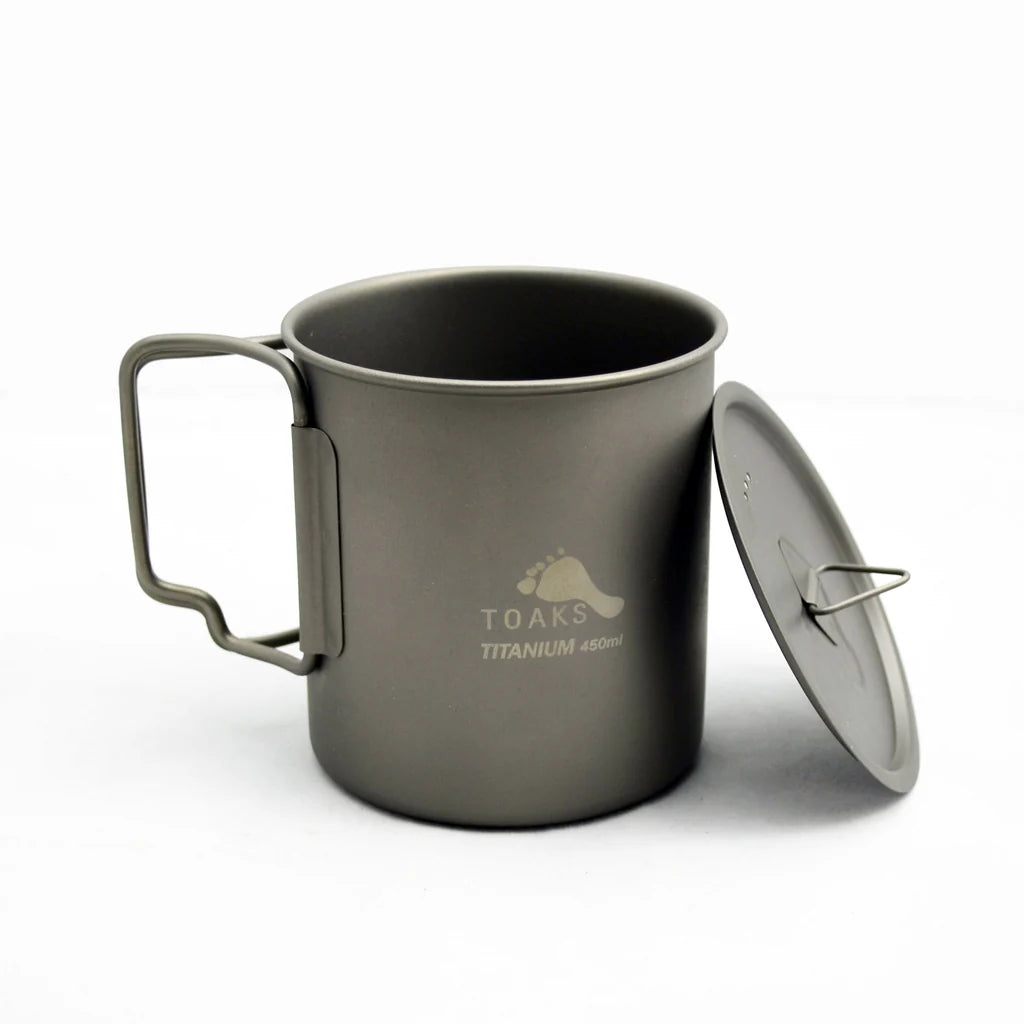 TOAKS 450 mL cup with lid leaning against the side.  